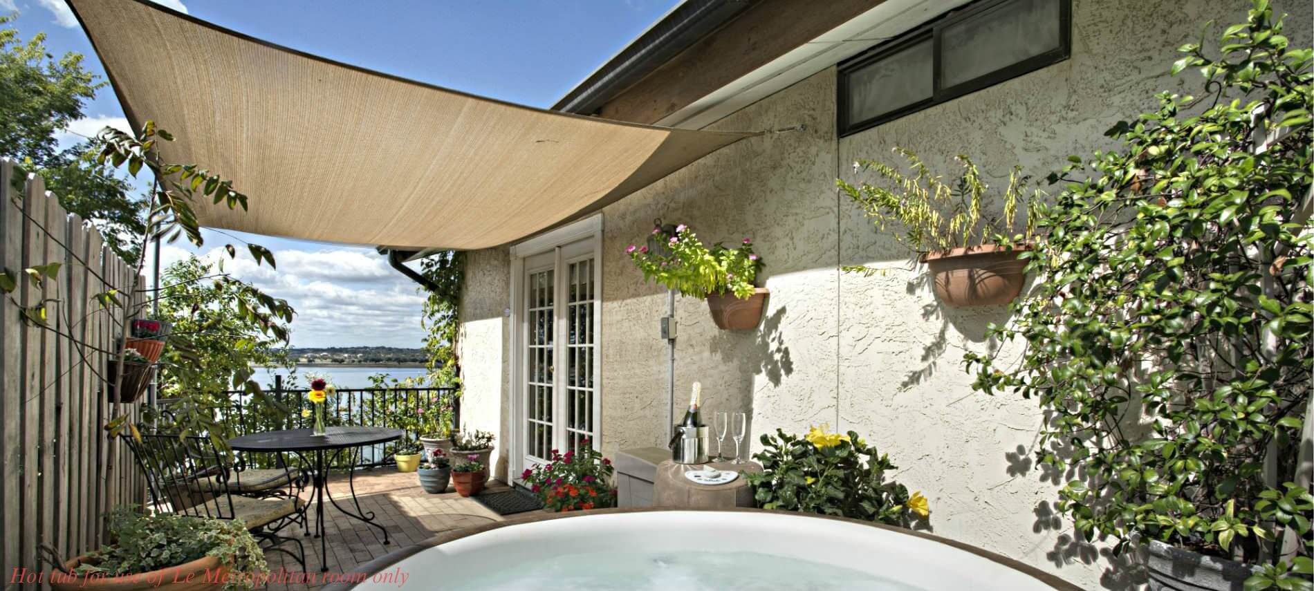 patio with table under canopy, view of lake, hot tub with watermark for use only by Le Metropolitain Room